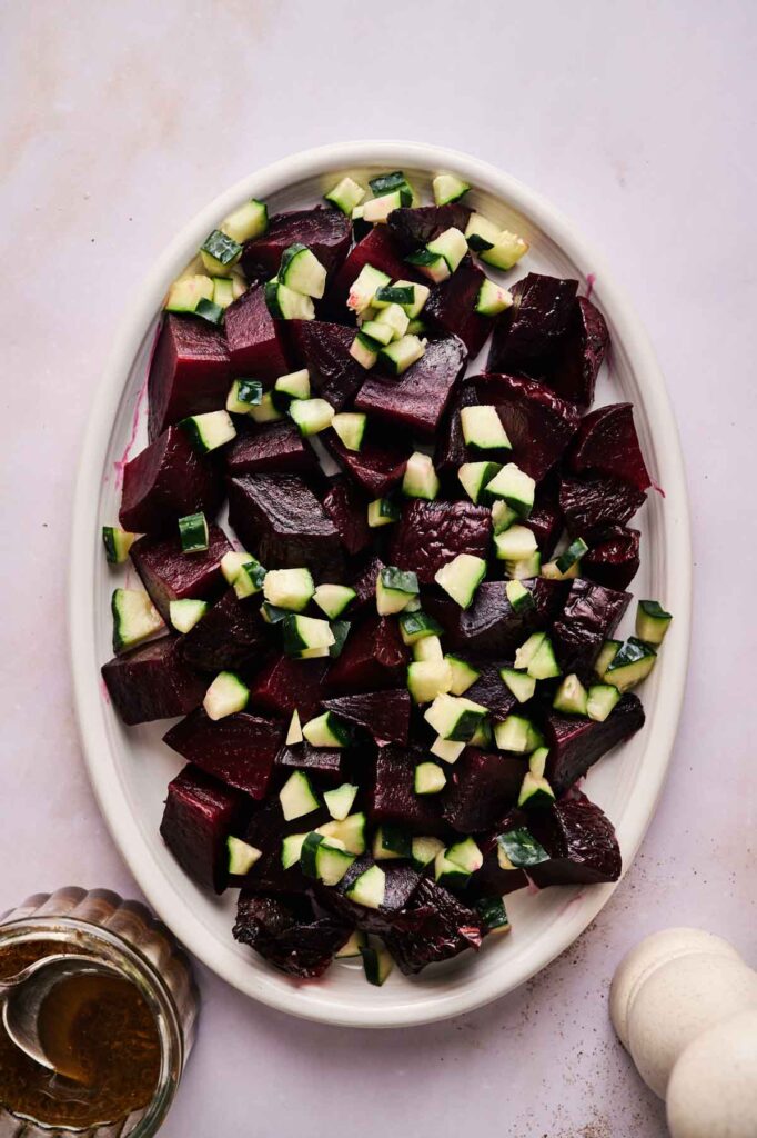 A plate of roasted beets and with cubed cucumbers.