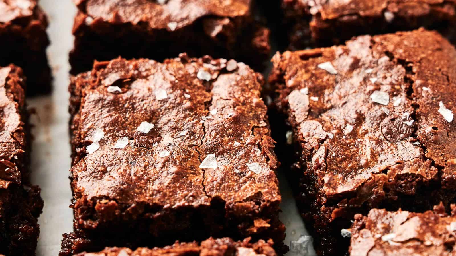 Close-up of chocolate brownies topped with sea salt flakes on a baking tray.