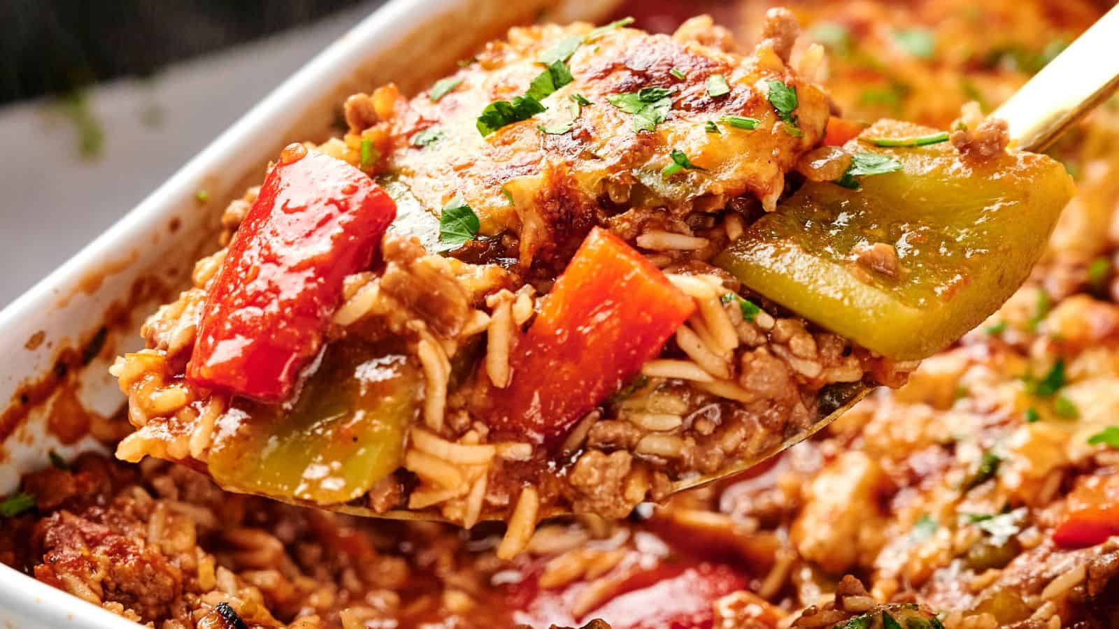 A spoonful of baked stuffed pepper casserole with ground meat, rice, and diced red and green bell peppers, garnished with parsley.