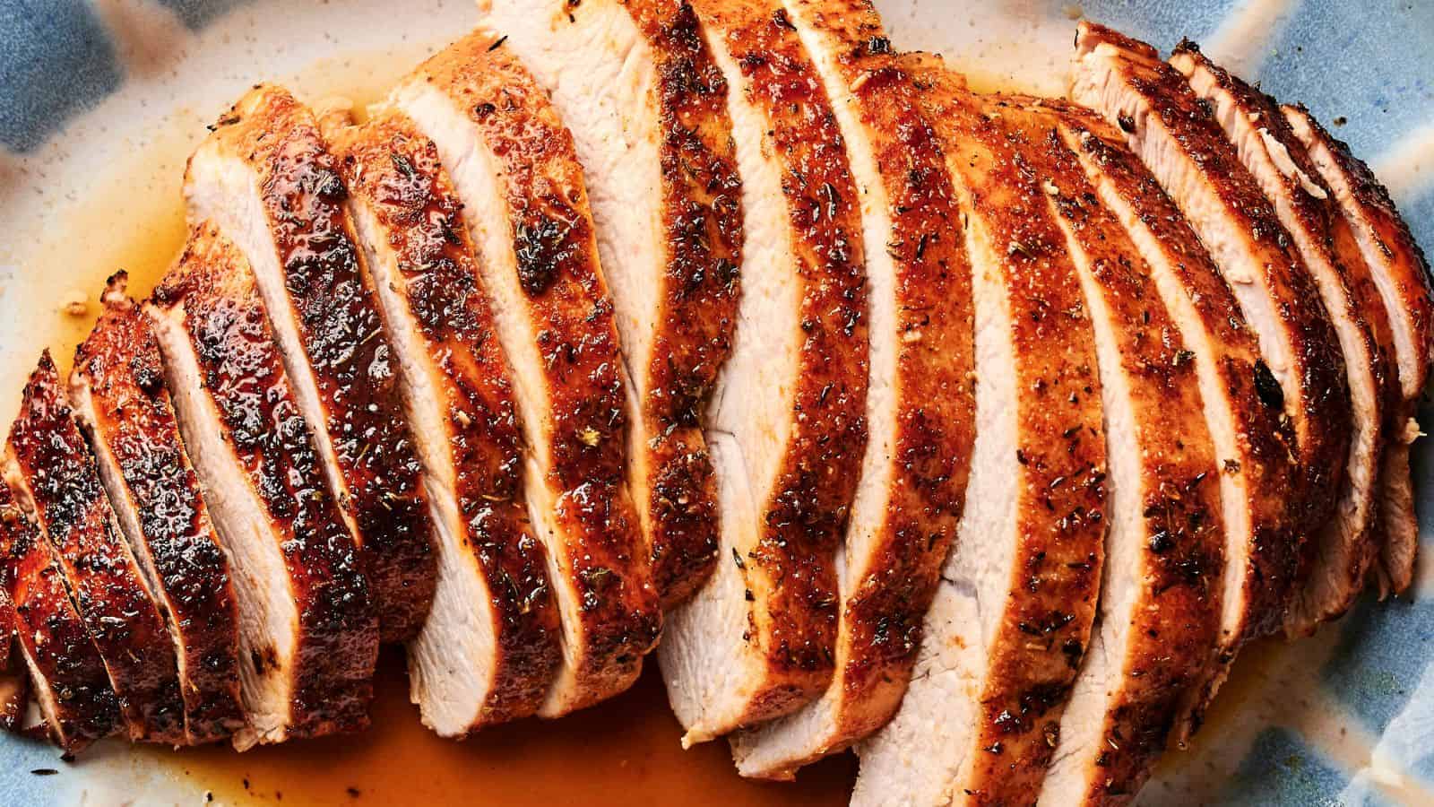 Sliced, seasoned, roasted turkey breast on a blue plate.