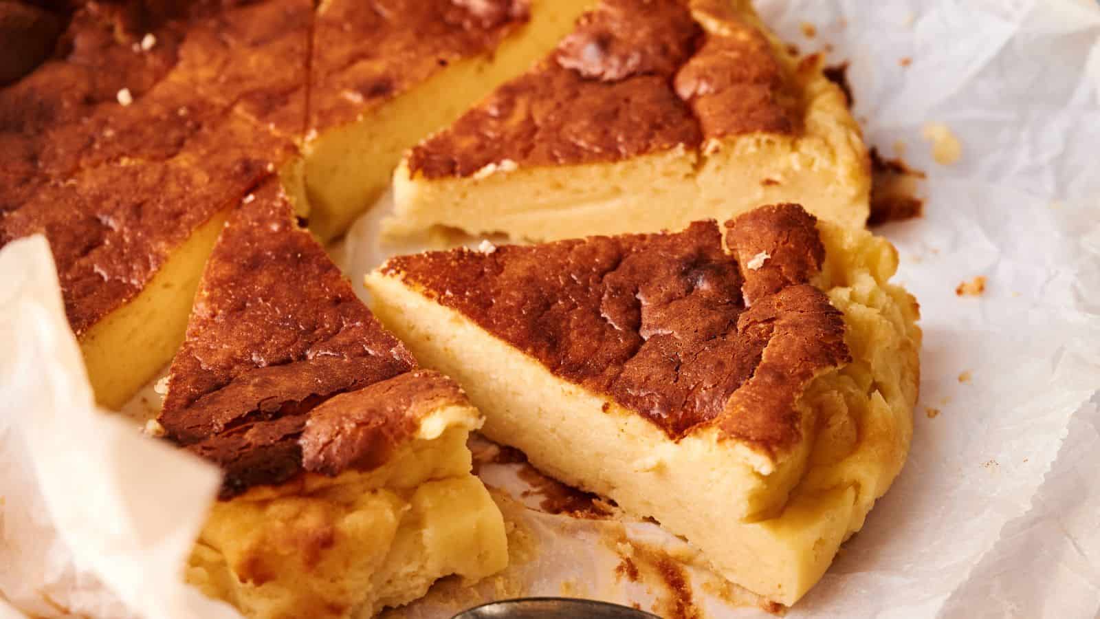 A close-up of several slices of a dense, golden-brown custard or cheesecake on parchment paper.