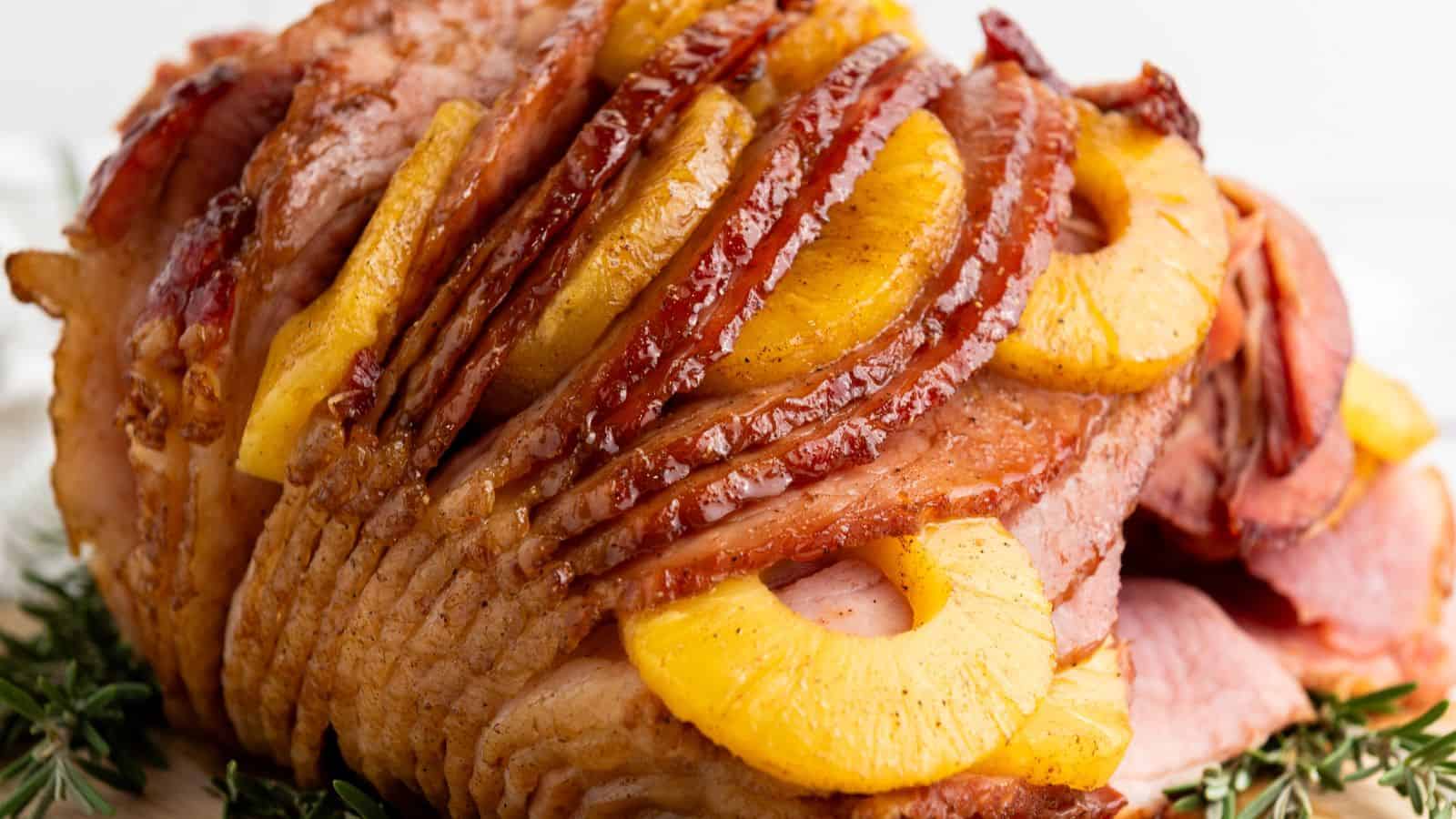 Glazed ham layered with pineapple slices and a hint of brown sugar, garnished with rosemary sprigs.