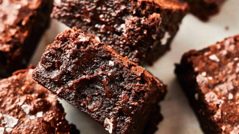 Close-up of several chocolate brownies with a rich, fudgy texture and a sprinkling of coarse salt on top.
