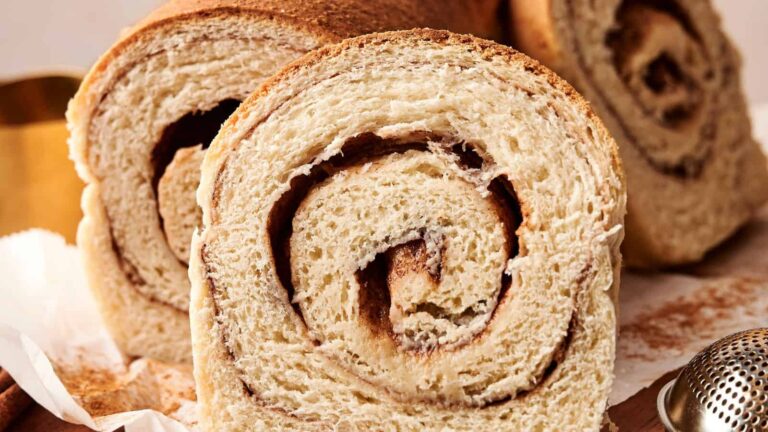 Close-up of sliced cinnamon swirl bread, showing the spiral pattern of cinnamon filling inside the soft, light-colored bread.