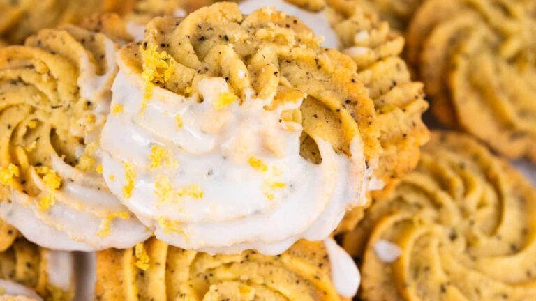 Close-up of lemon poppy seed cookies with a white glaze and lemon zest sprinkled on top.
