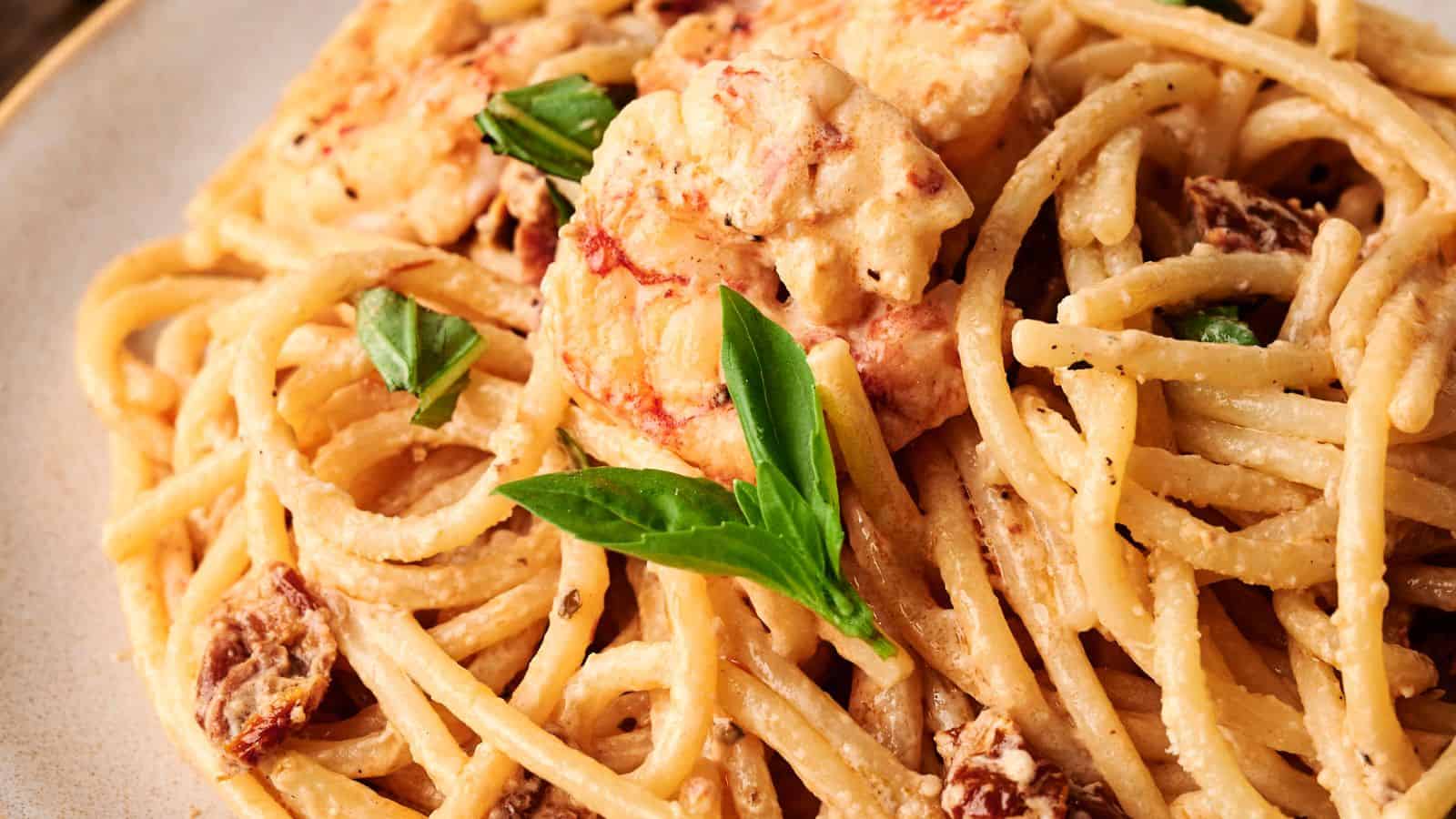A plate of creamy spaghetti with shrimp, sun-dried tomatoes, and fresh basil leaves.