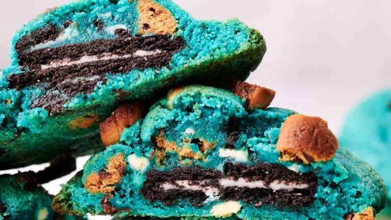 Close-up of bright blue cookies with chocolate chips and sandwich cookies inside, stacked on top of each other.