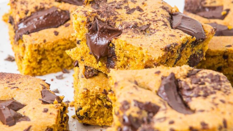 Close-up of several pumpkin bars with chunks of dark chocolate on top, showing their moist texture and golden-orange color.