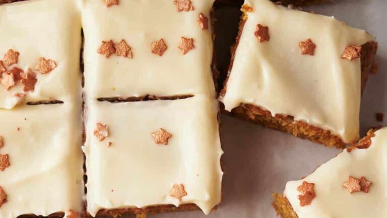 Rectangular pieces of cake with white icing and small star-shaped sprinkles on top, arranged on a white surface.
