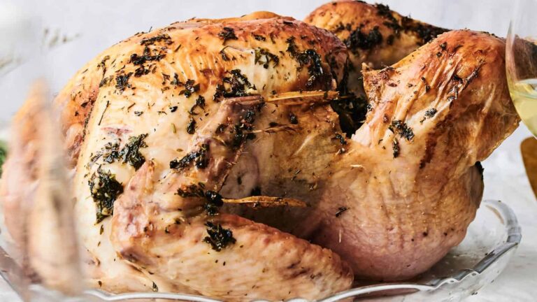 A cooked turkey with herbs on it.