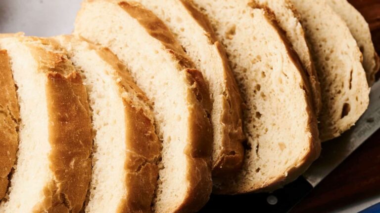 Several slices of white bread are arranged in a row, showing a soft, airy texture and a light golden-brown crust.