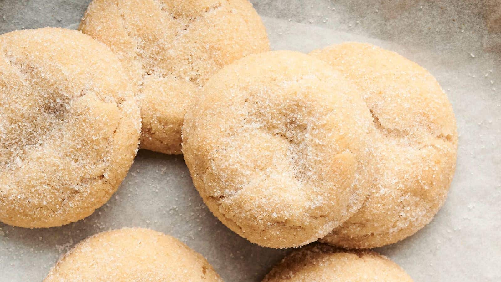 Close-up of six sugar-coated cookies on parchment paper.