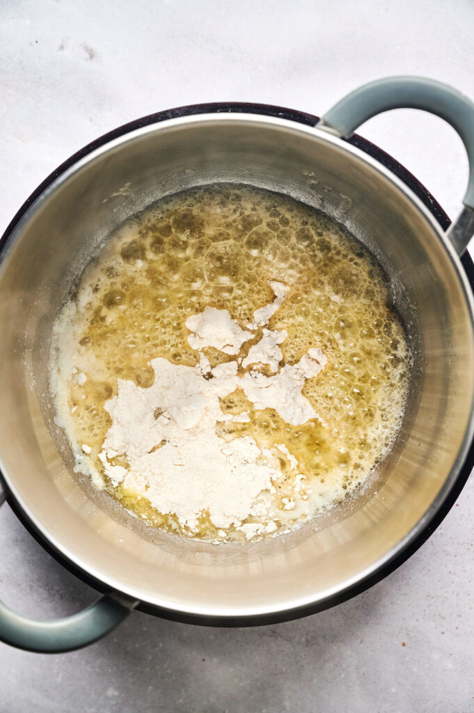 A saucepan containing melted butter and flour being mixed together on a light countertop, likely creating a roux for dishes like Air Fryer Beef Moussaka.