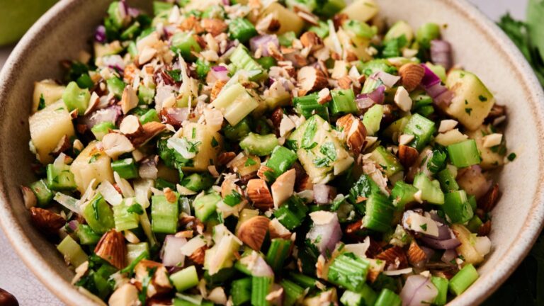 A bowl of chopped celery, apples, red onions, almonds, and parsley mixed together.