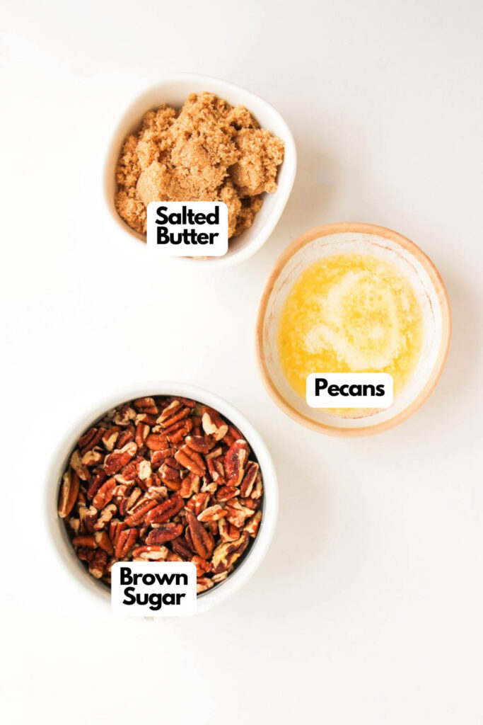 Three bowls on a white surface containing brown sugar, melted salted butter, and chopped pecans—essential ingredients for making Pumpkin Pecan Pie Bars—each labeled accordingly.