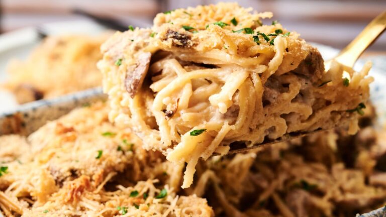 Close-up of a serving of creamy baked spaghetti casserole with shredded chicken, mushrooms, and a golden breadcrumb topping.