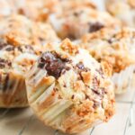 Close-up of S'mores Muffins with a crumbly topping and gooey chocolate chips, cooling on a wire rack.