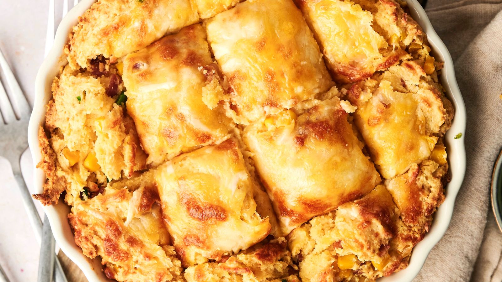 A baked casserole with a golden, flaky crust cut into squares, showing a filling that includes corn and other ingredients.