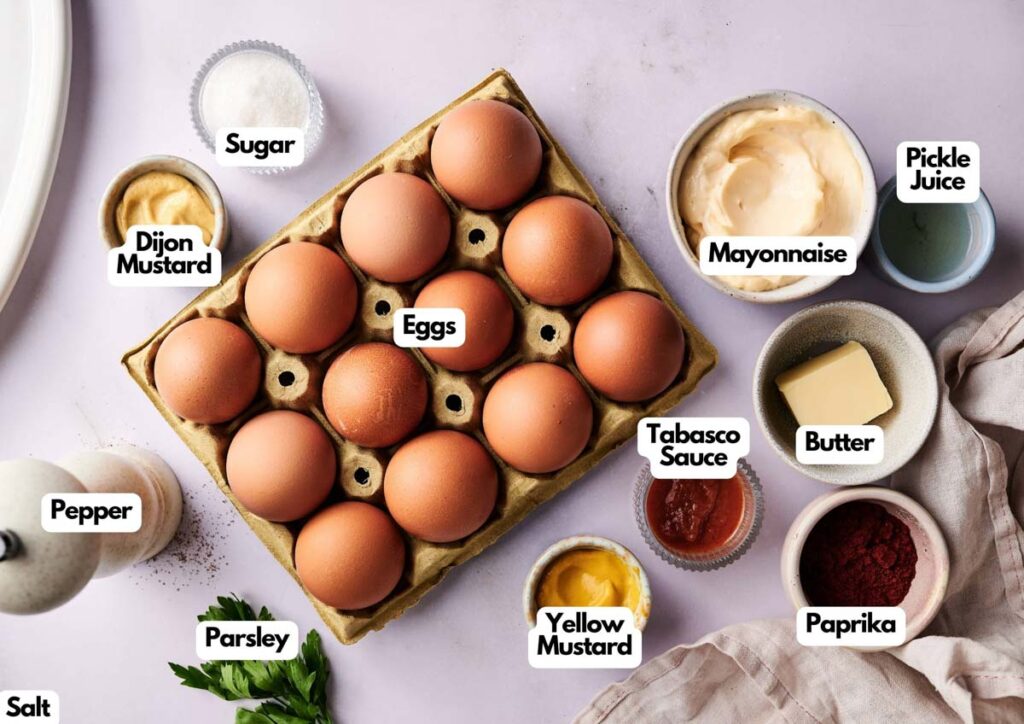 A dozen brown eggs in a carton are surrounded by labeled bowls of mayonnaise, pickle juice, butter, and spices&mdash;everything you need to create irresistible Million Dollar Deviled Eggs.