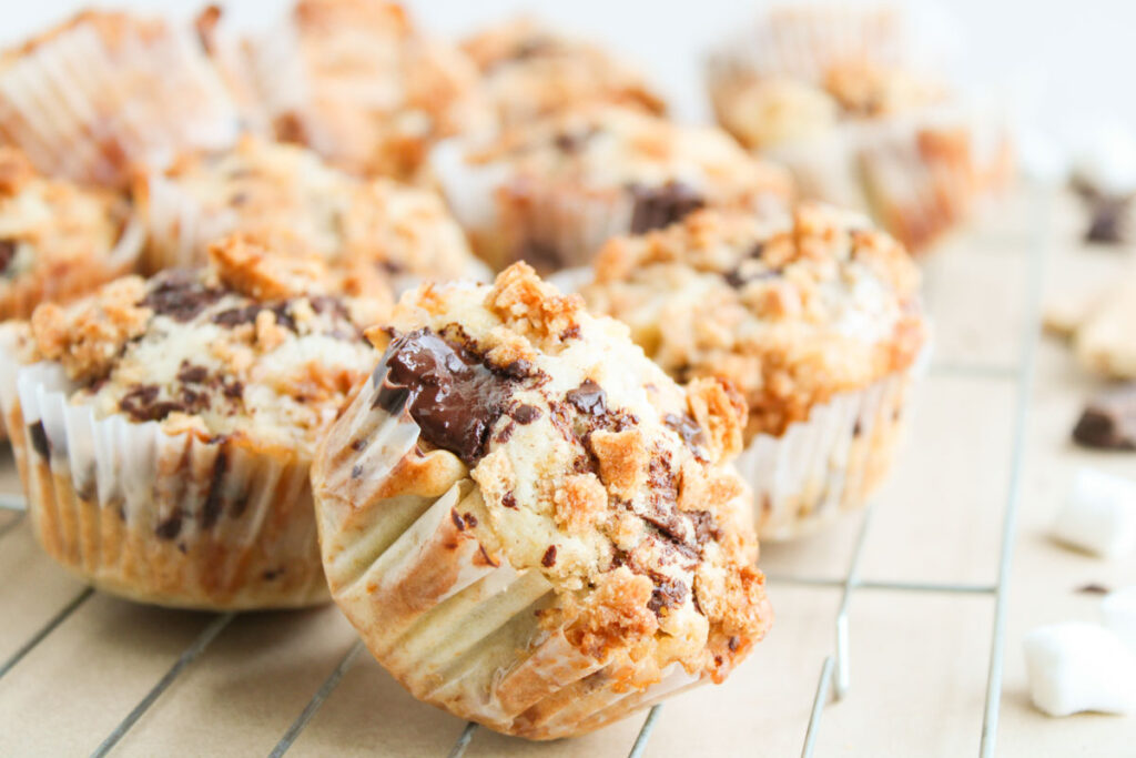 A close-up of S'mores Muffins with crumb topping and chocolate chips, arranged on a cooling rack.