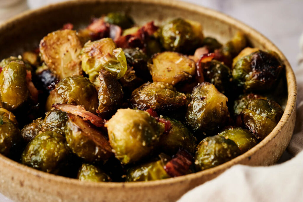 A bowl of Brussels Sprouts with Bacon features perfectly roasted sprouts tossed with crispy bacon pieces for a savory, irresistible side dish.