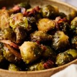 A bowl of Brussels Sprouts with Bacon features roasted sprouts tossed with crispy pieces of savory bacon.