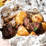Tender beef chunks and roasted potatoes in a foil packet, infused with rich garlic butter. This Garlic Butter Steak and Potatoes Foil Packet is finished with fresh herbs for a flavorful, easy meal.