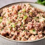 A bowl of Ham Salad with chopped ham, celery, onions, and herbs, all mixed with creamy mayonnaise.