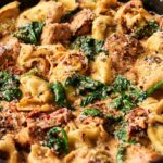 Creamy Marry Me Chicken Tortellini with spinach, sun-dried tomatoes, and chunks of seasoned chicken, topped with grated parmesan and black pepper.