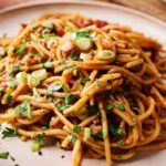 A plate of Mexican Spaghetti with meat sauce, topped with chopped green onions and fresh parsley.