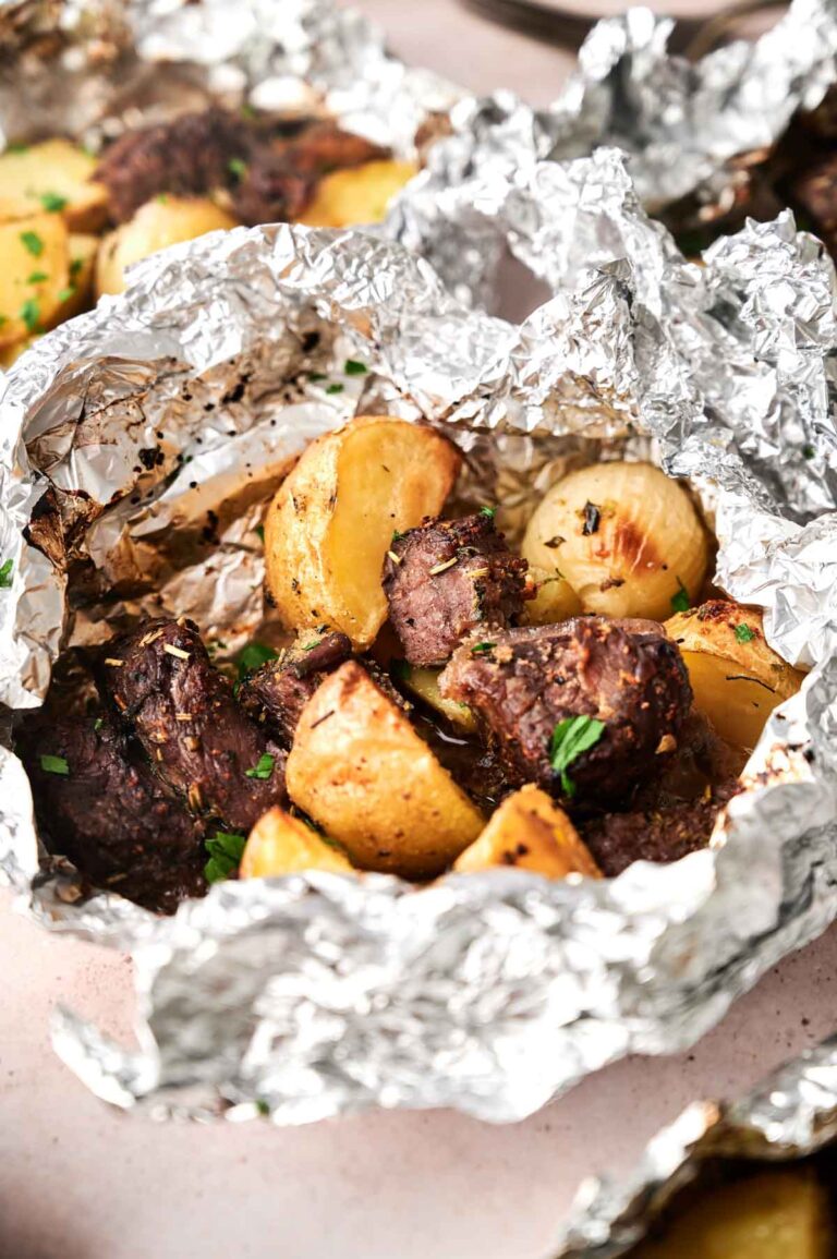 Chunks of beef and roasted potatoes in a Garlic Butter Steak and Potatoes Foil Packet, seasoned with herbs and garnished with chopped parsley.