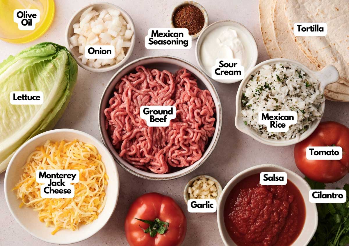 A variety of taco ingredients are arranged in bowls, including ground beef, rice, cheese, lettuce, tomato, salsa, onion, garlic, cilantro, and sour cream—perfect for crafting a Grilled Cheese Burrito or loading up your favorite tortilla.