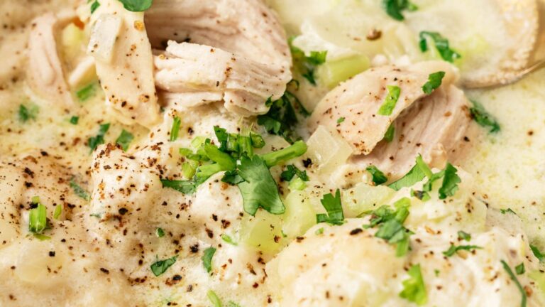 Close-up of creamy chicken and dumplings topped with chopped cilantro and black pepper.