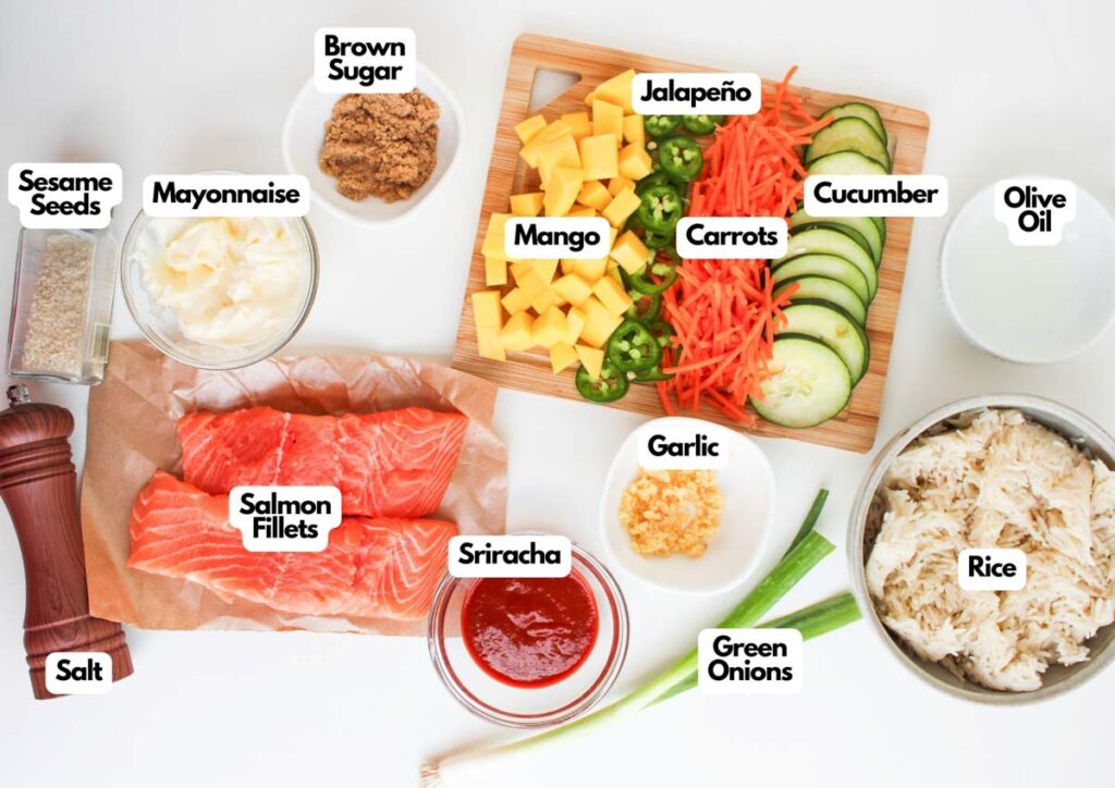 Assorted ingredients for Spicy Salmon Bowls, including salmon fillets, rice, vegetables, mango, sauces, seasonings, and condiments, arranged on a white surface.