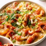 A bowl of Crawfish Etouffee topped with chopped green onions and parsley, featuring a thick, savory sauce and generous pieces of crawfish.