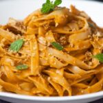 A close-up of Hidden Veggie Pasta: fettuccine coated in a creamy orange sauce, garnished with fresh herbs and breadcrumbs, served in a white bowl.