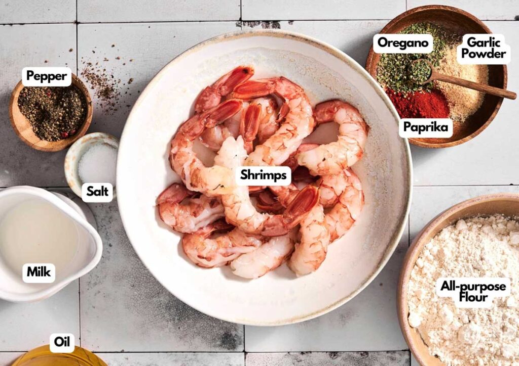 A bowl of raw shrimp, soon to become delicious fried shrimp, is surrounded by labeled ingredients: pepper, salt, milk, oil, all-purpose flour, paprika, oregano, and garlic powder.