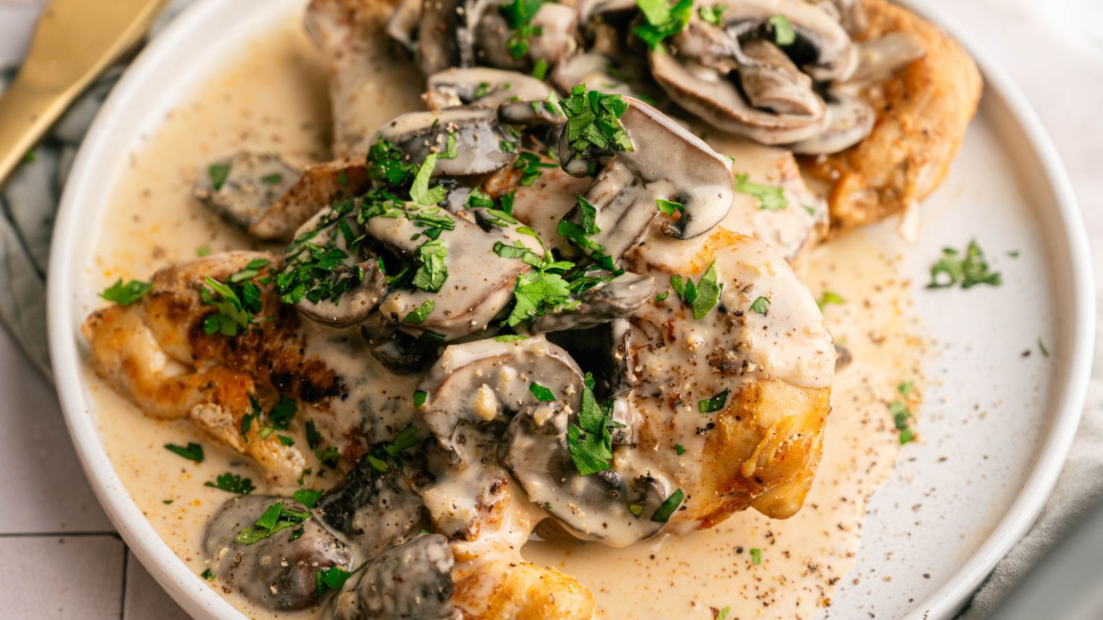 Plate of chicken covered in a creamy mushroom sauce, garnished with chopped parsley.