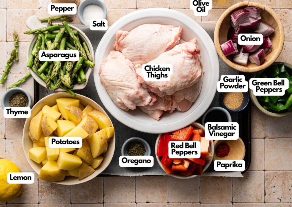 Sheet Pan Chicken Thighs and Veggies: Juicy chicken thighs in a bowl, surrounded by potatoes, asparagus, onion, bell peppers, lemon, thyme, oregano, olive oil, vinegar, garlic powder, salt, pepper, and paprika.