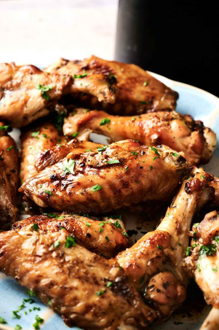 A plate of crispy air fryer turkey wings garnished with chopped herbs, displayed on a light-colored dish.