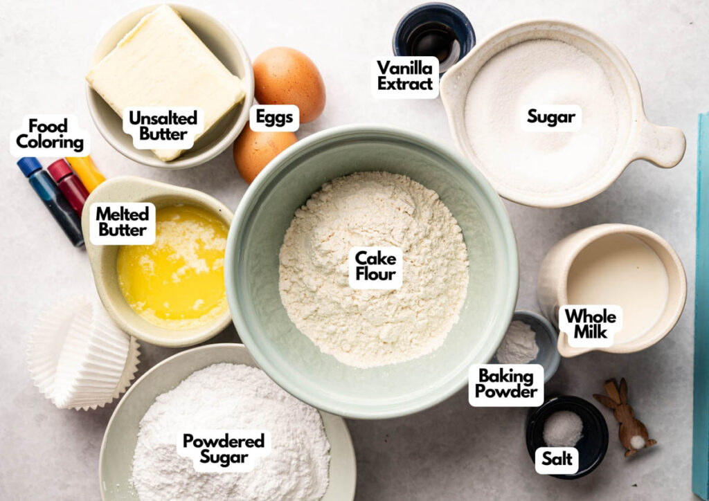 Various labeled baking ingredients in bowls, including cake flour, sugar, eggs, whole milk, unsalted butter, melted butter, powdered sugar, baking powder, vanilla extract, salt, and food coloring&mdash;perfect for making festive Easter Cupcakes.