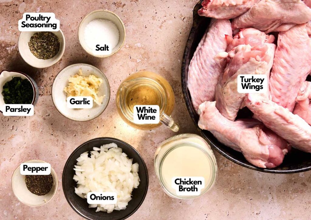 Ingredients for cooking are arranged on a surface, including raw turkey wings perfect for Air Fryer Turkey Wings, chopped onions, parsley, garlic, poultry seasoning, salt, pepper, white wine, and chicken broth.