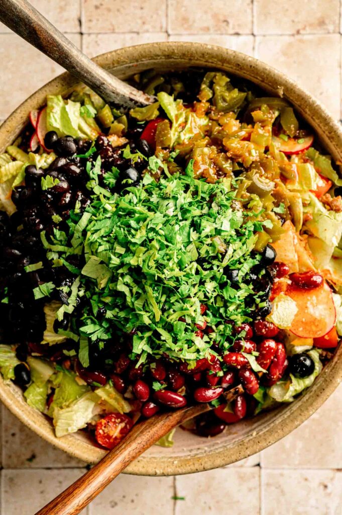 A large bowl of Doritos Taco Salad with black beans, kidney beans, black olives, jalape&ntilde;os, fresh cilantro, and Catalina dressing, ready to serve.
